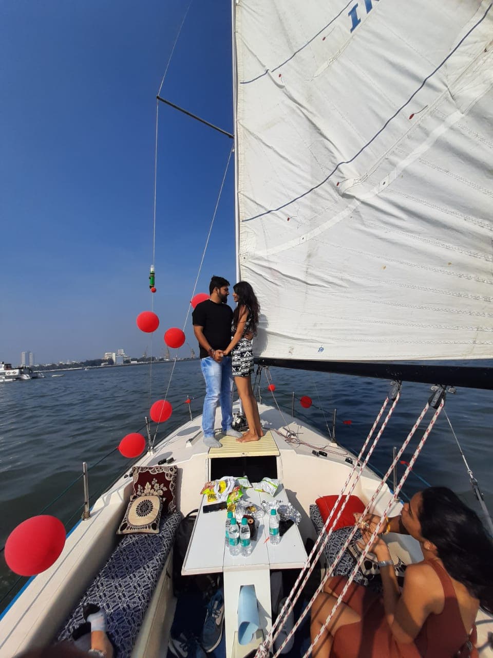 A couple sharing a private moment at the bow under sail, Mumbai skyline behind