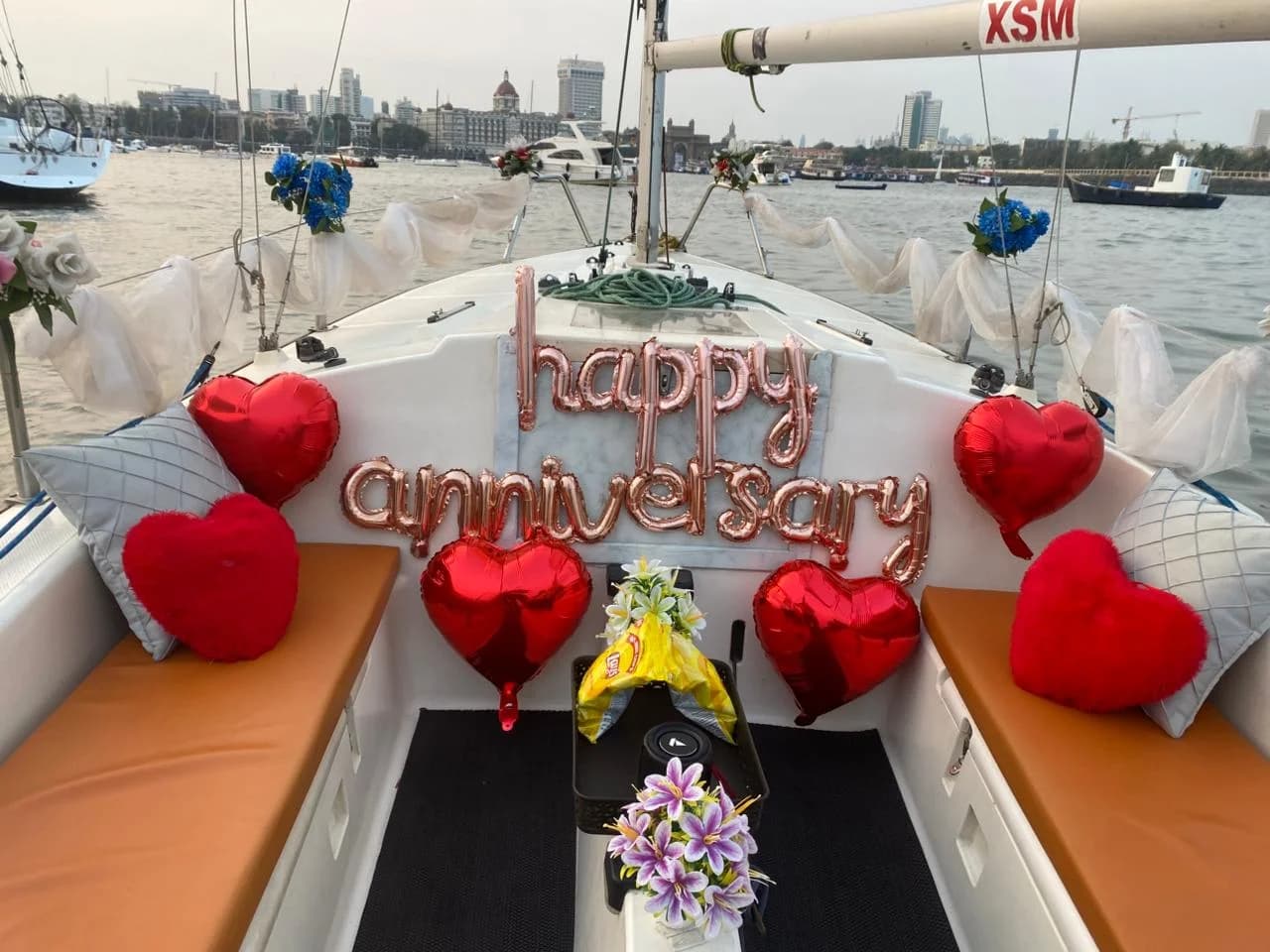 A happy anniversary balloon display on the bow with the Mumbai skyline behind