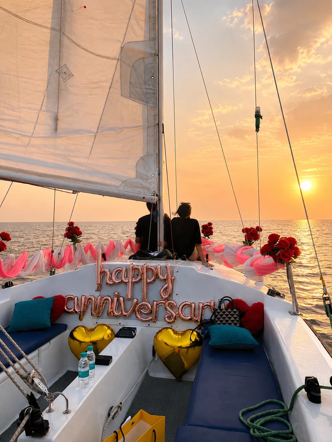 A couple silhouetted at the bow under a happy anniversary balloon display at sunset