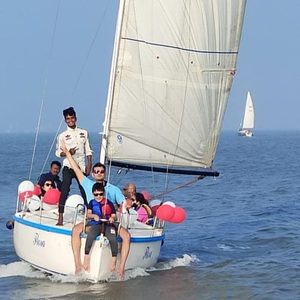 A young guest at the helm with the skipper alongside as the sailboat heels under sail