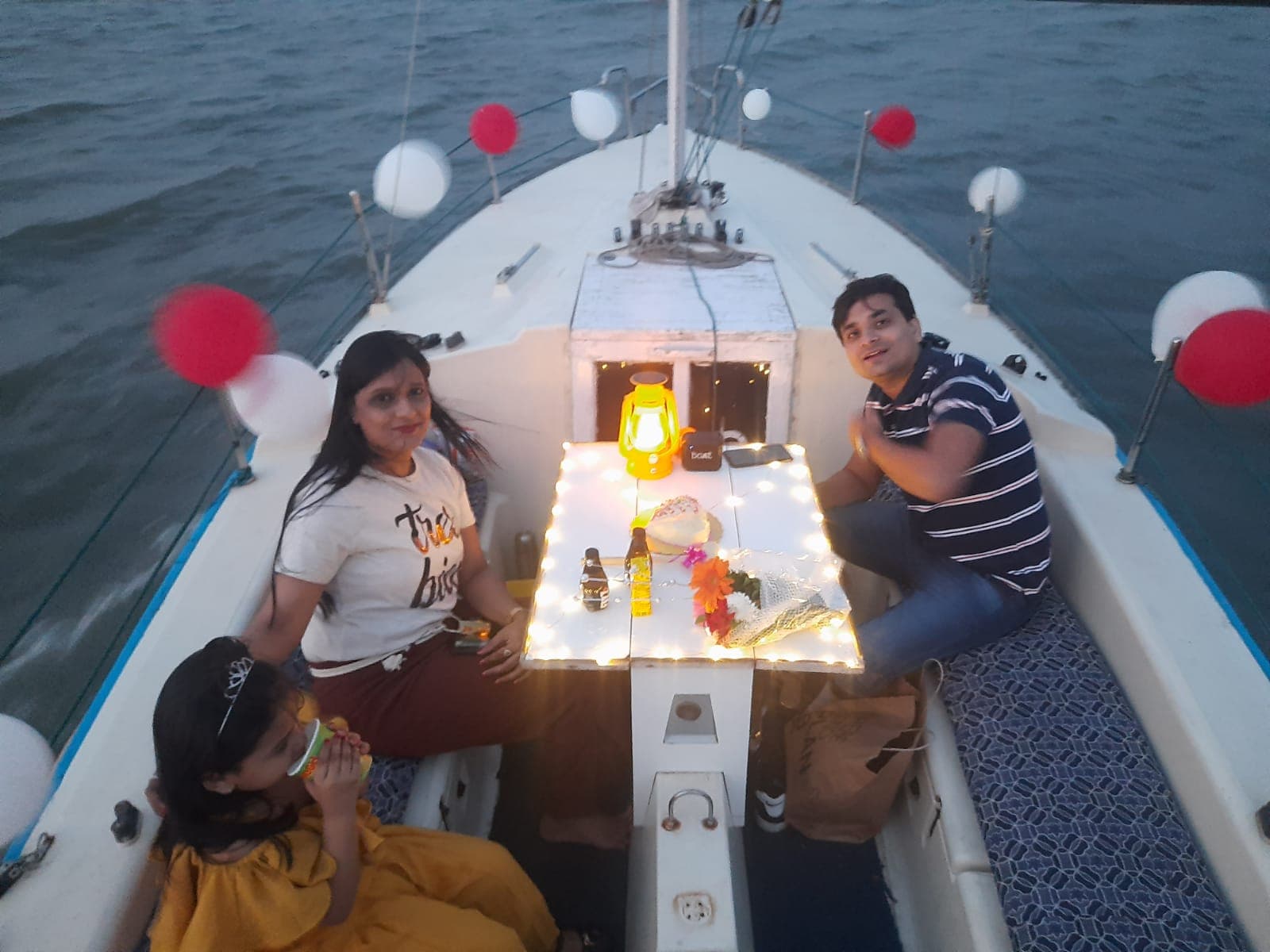 A family gathered on the bow at dusk with a passing motor yacht behind