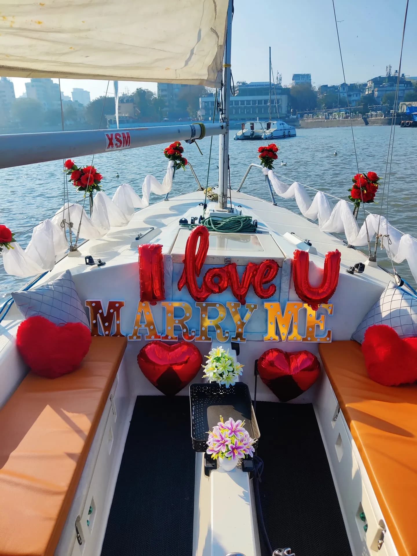 A proposal set-up on the bow reading I Love U, Marry Me, decorated with roses and heart balloons