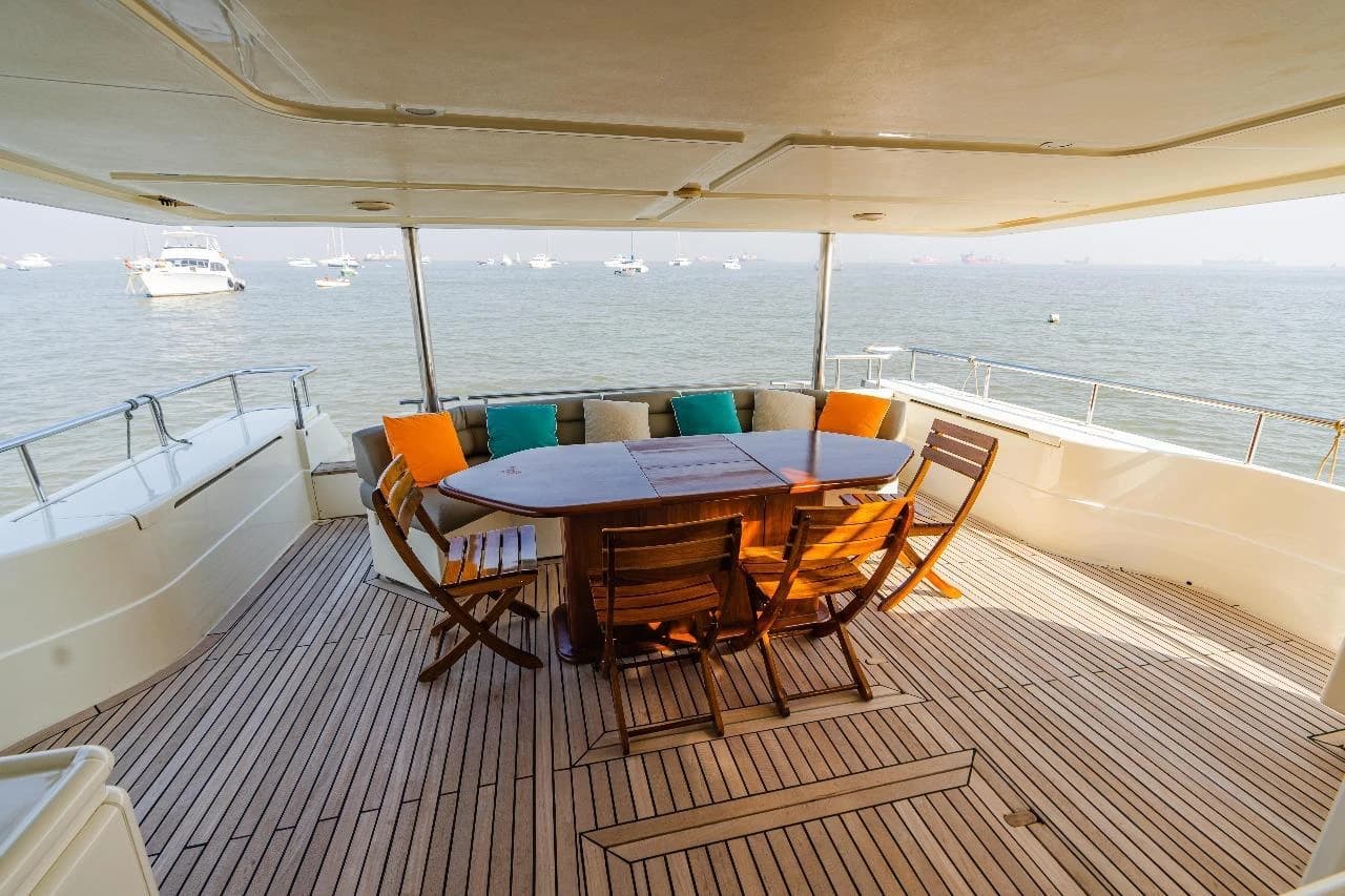Flybridge dining table and chairs in daylight, with moored boats on the harbour