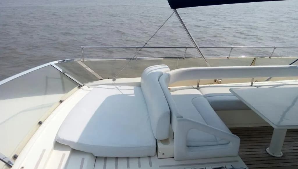 Flybridge sun pad seating beside the dining table, under the bimini