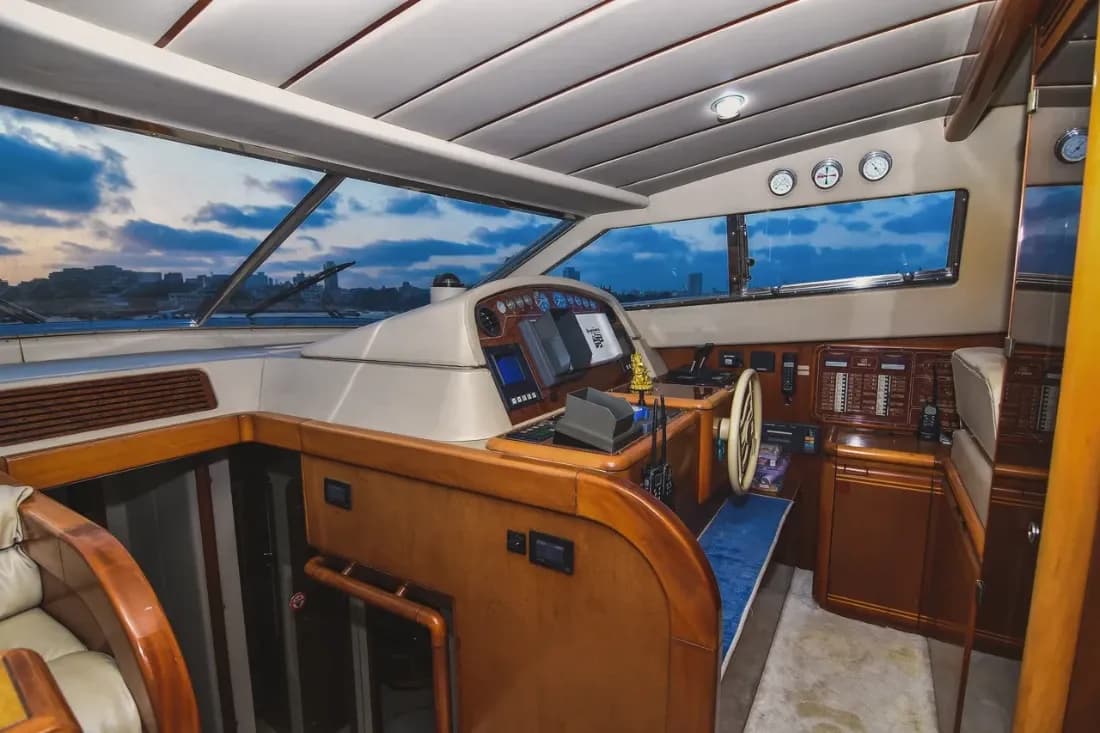 The lower helm station at dusk, with wood trim and the Mumbai skyline through the windows