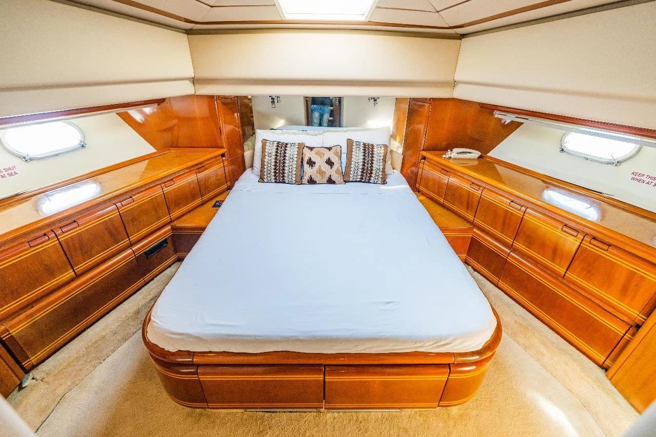 A second wood-panelled cabin with a made-up double bed and portholes
