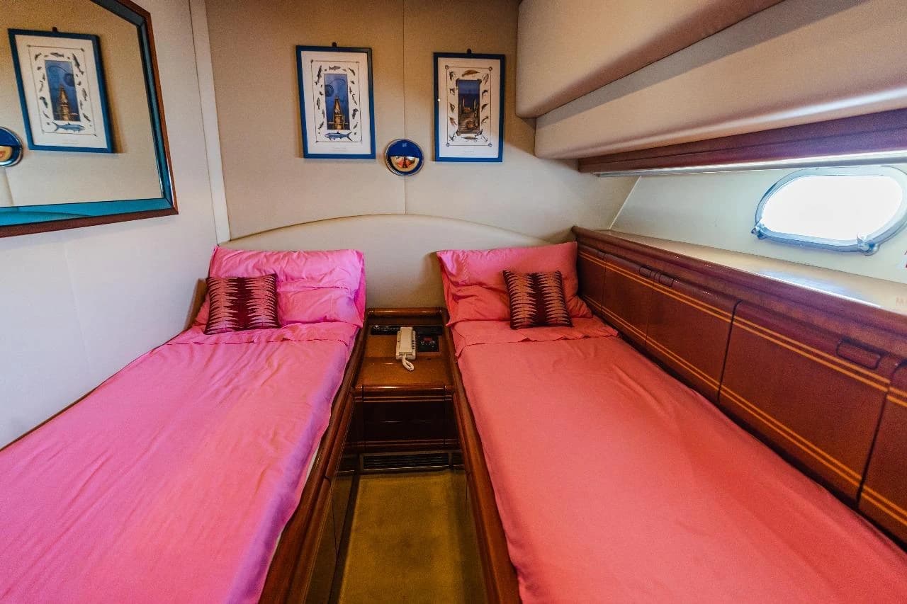 A twin-bed cabin with pink bed linen and wood panelling