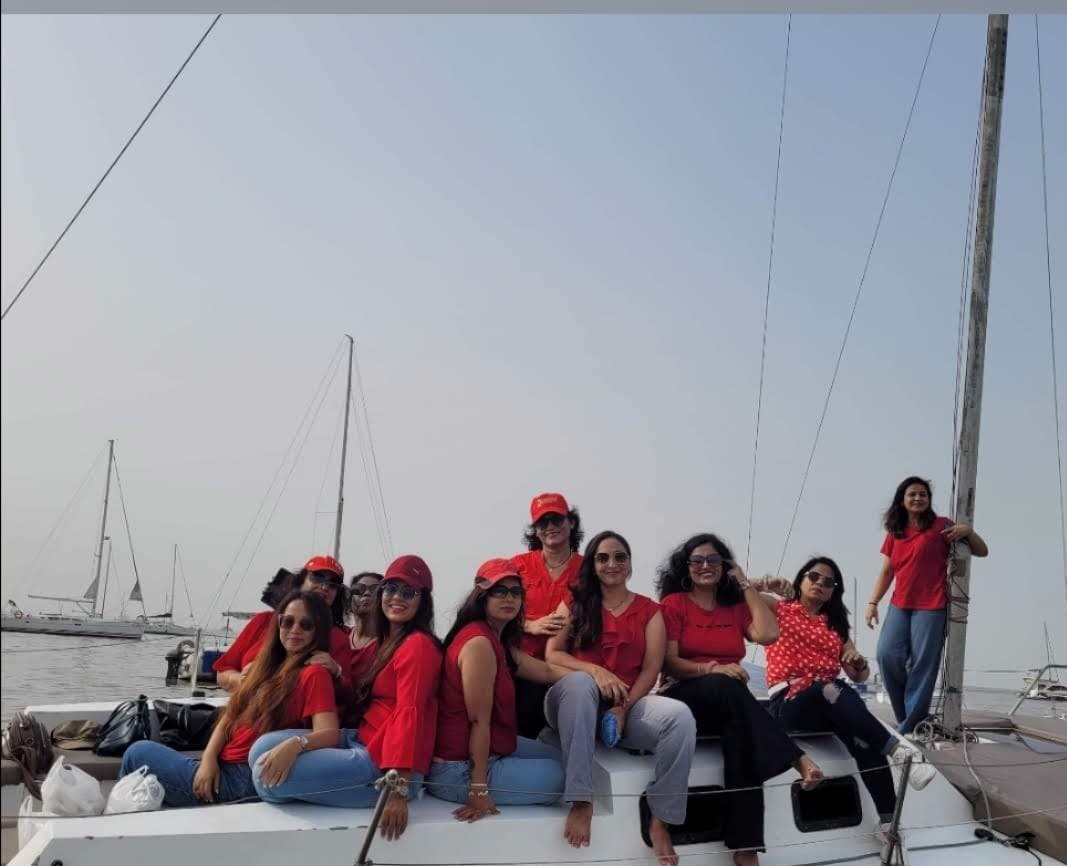 A large group of guests in matching red seated along the deck under sail