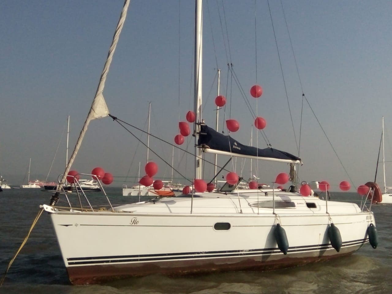 Flo decked out in red balloons at anchor, her nameplate visible on the bow