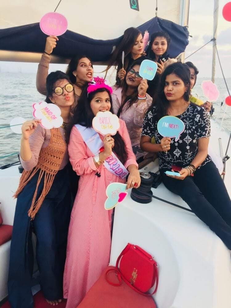 A bachelorette group on deck with a bride-to-be sash and photo-booth props