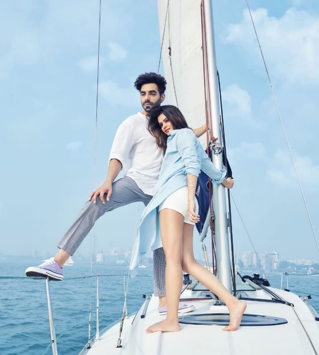 A couple posed at the bow with the Mumbai coastline behind