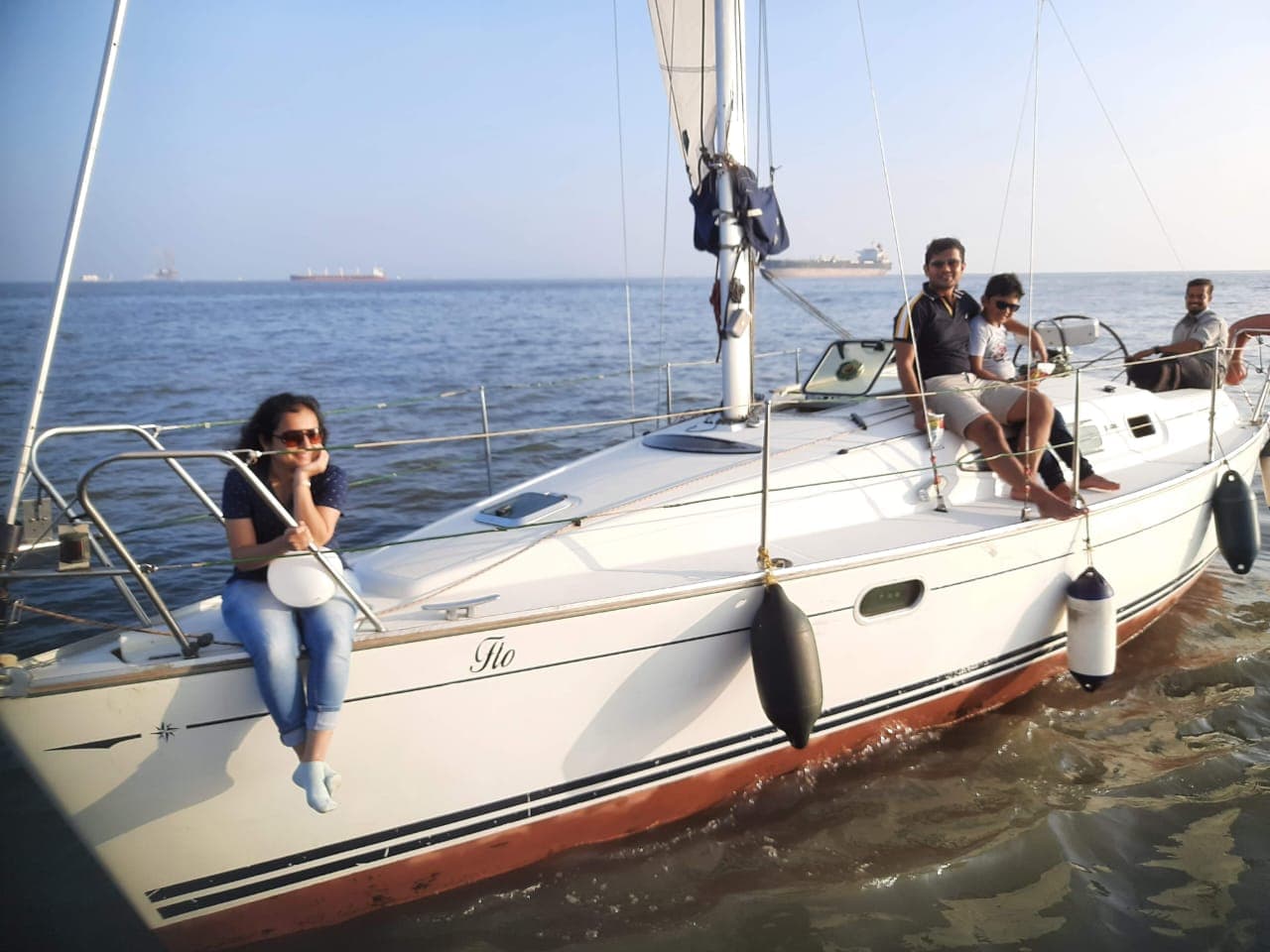 A group of guests seated along the deck and bow as Flo sails past passing ships