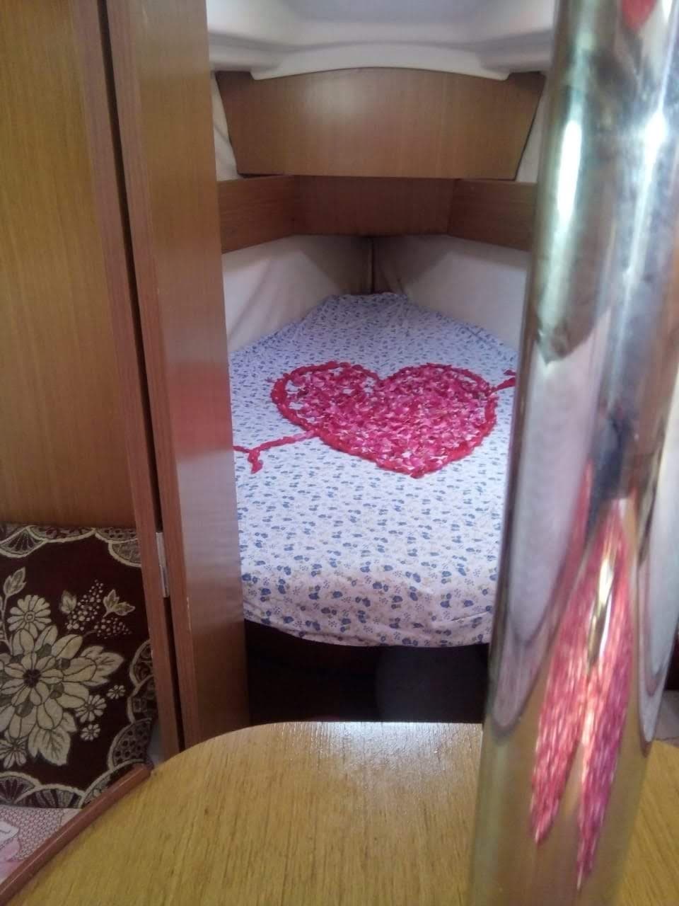 A heart traced in rose petals on the forward cabin berth