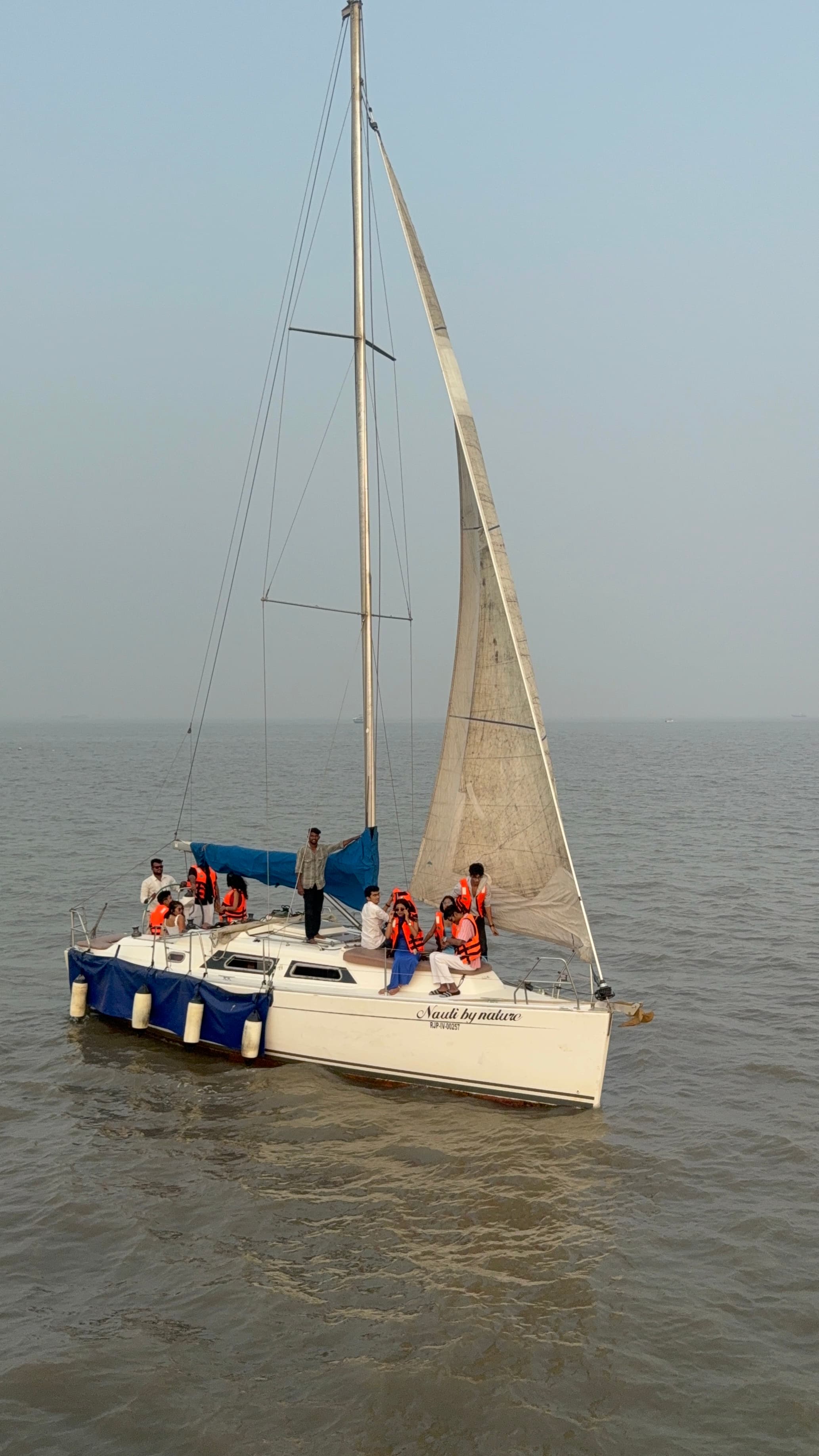 A large family group in life jackets seated along the deck under sail