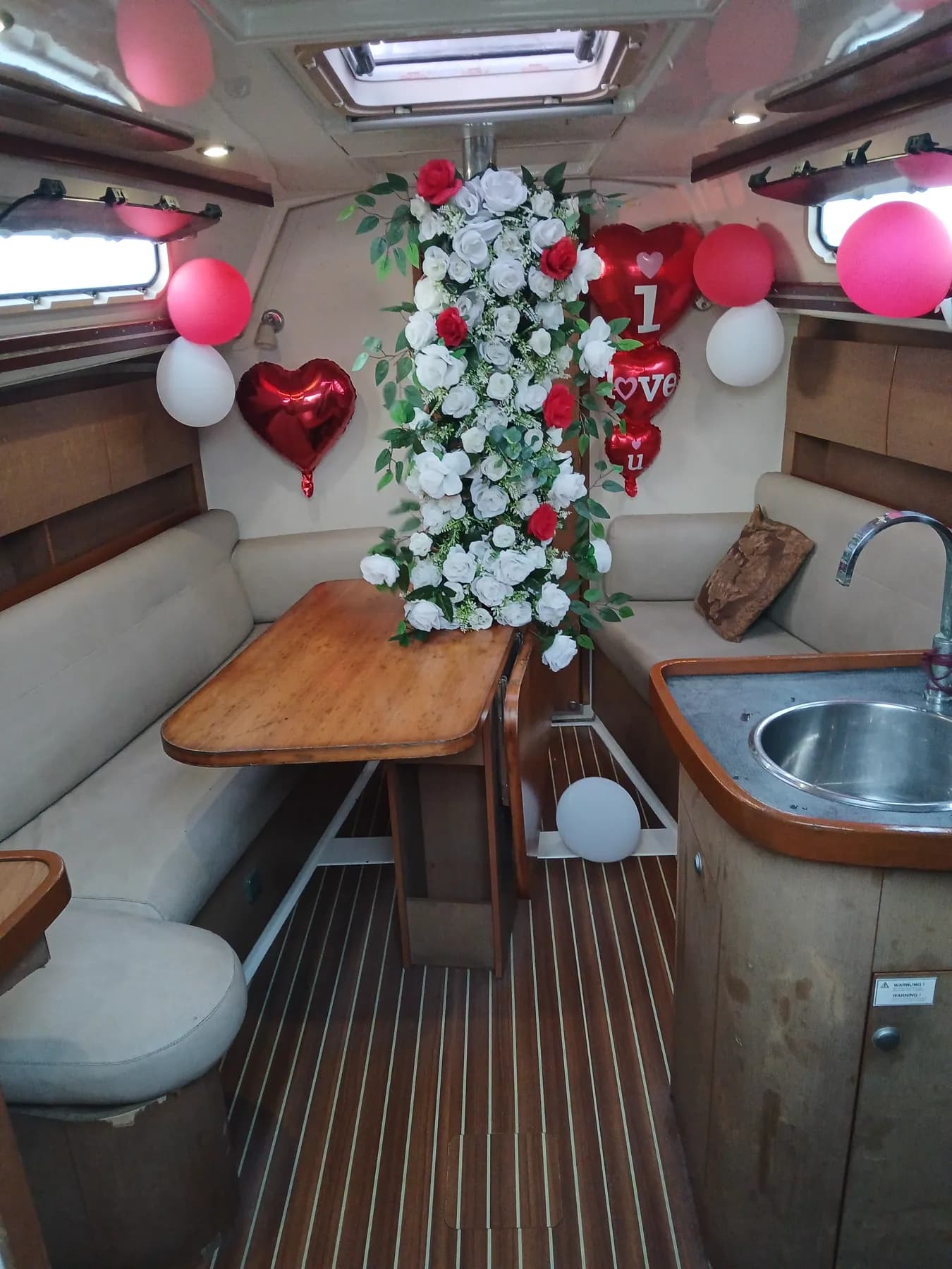 The full saloon set up for a proposal, with a rose garland, balloons and cushioned bench seating