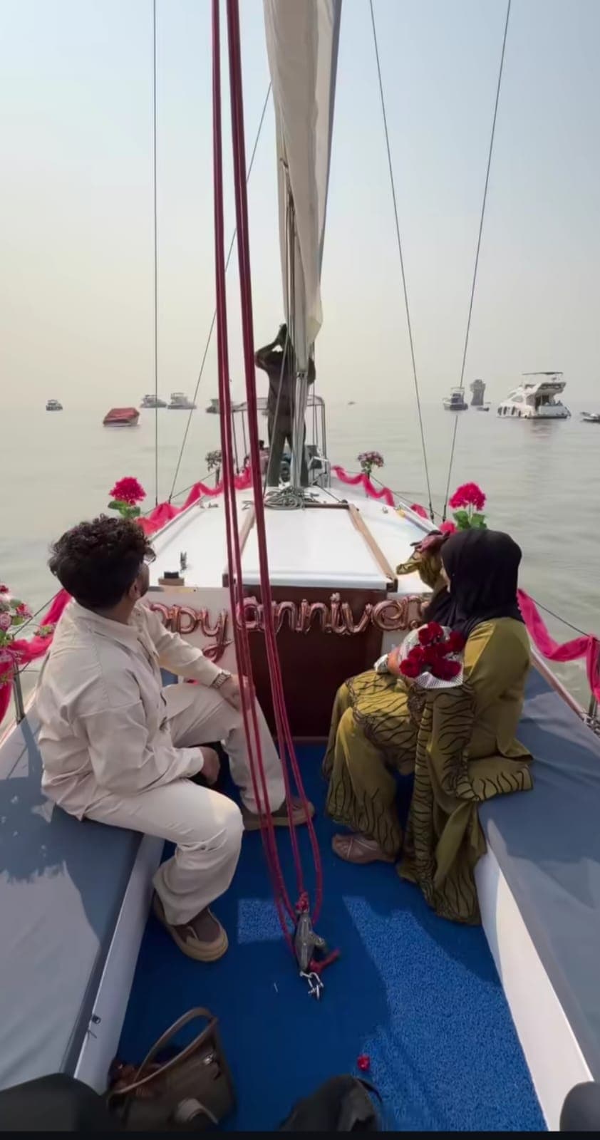 A couple seated at the bow beside a happy anniversary balloon display