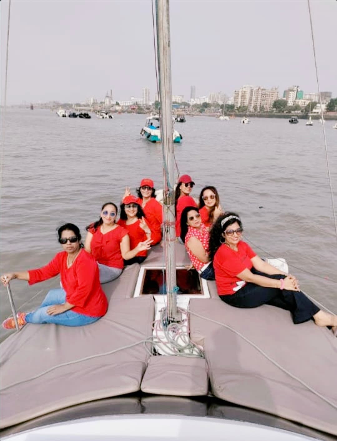 A large group of guests in matching red seated along the bow under sail