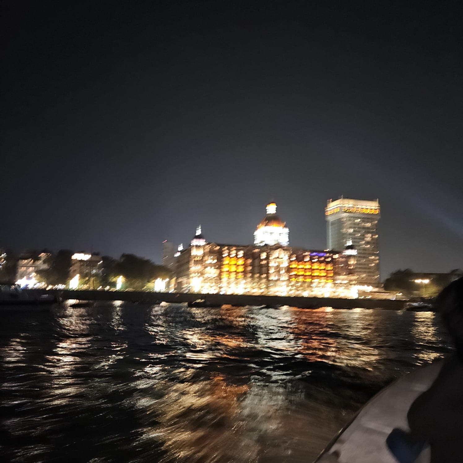 The Taj Mahal Palace lit up at night, seen from the boat