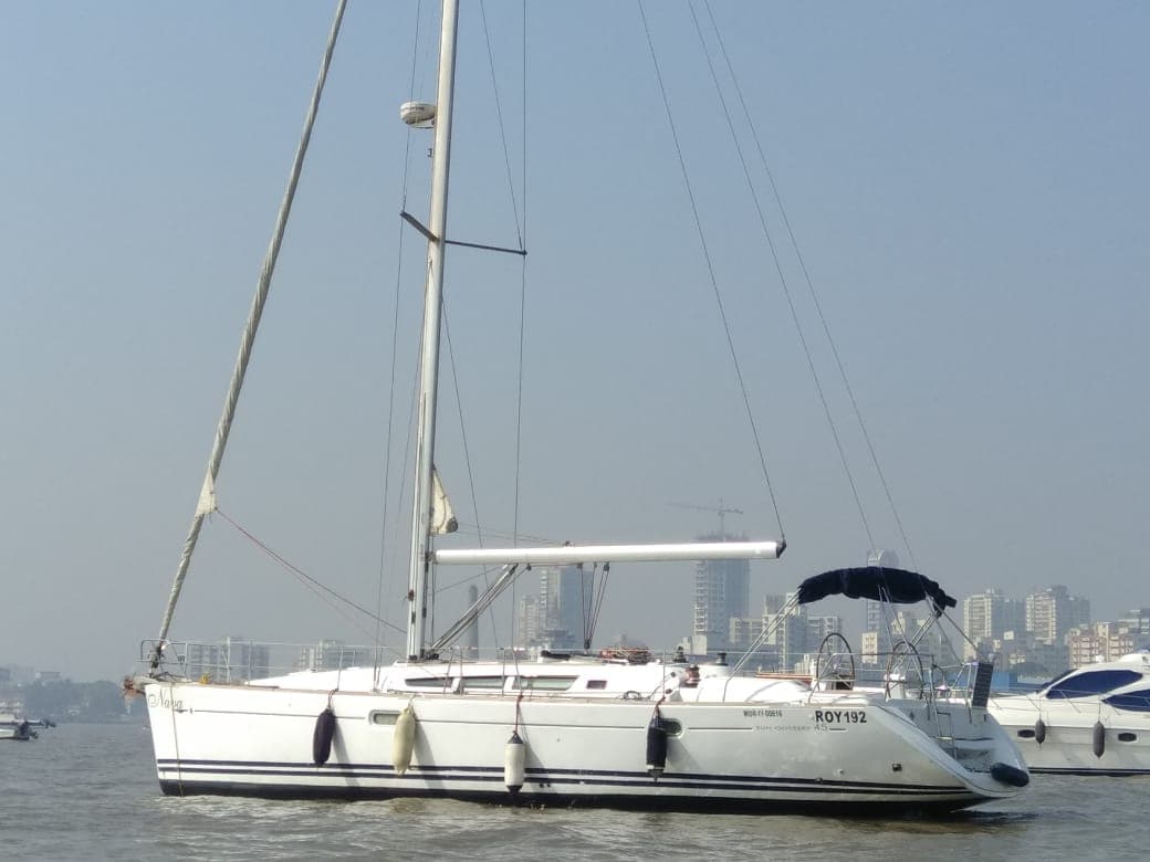 Nava's side profile at anchor with the Mumbai skyline behind
