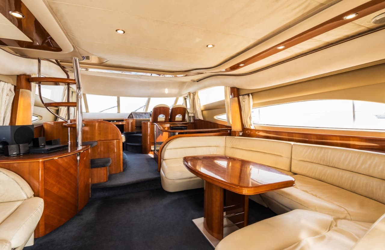Princess 61 main saloon with cream leather seating, dining table and cherry wood joinery