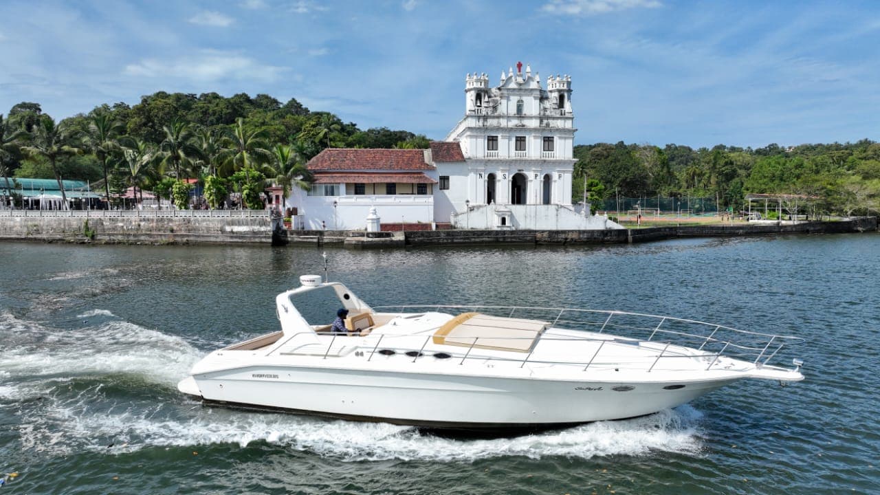 The Sea Ray under way past a riverfront church near Panjim, Goa