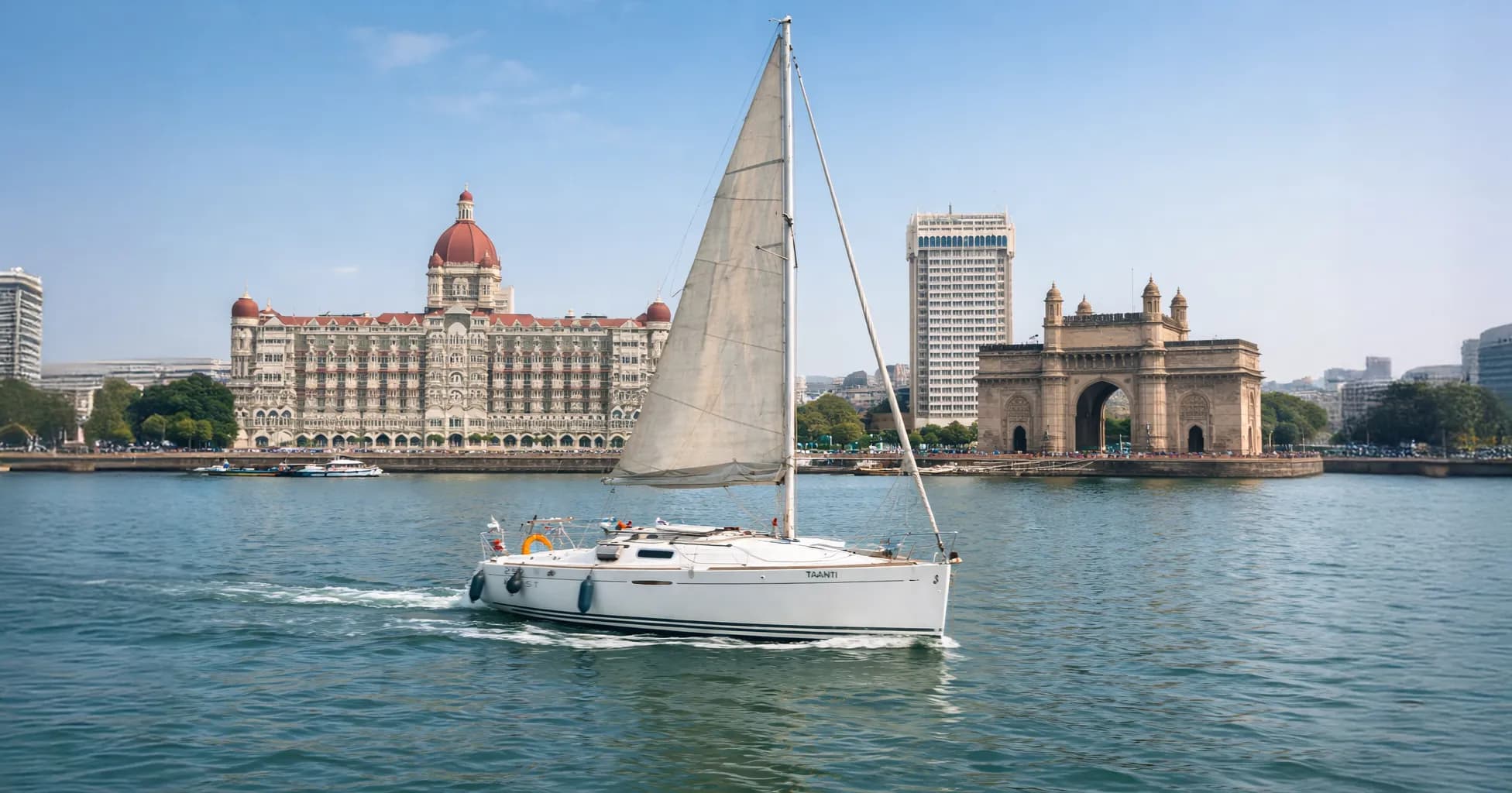 Taanti under sail with the Taj Mahal Palace and Gateway of India behind