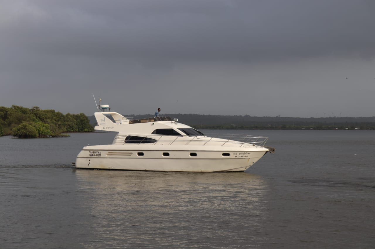 Taj Exotica under way on the Mandovi with mangroves behind