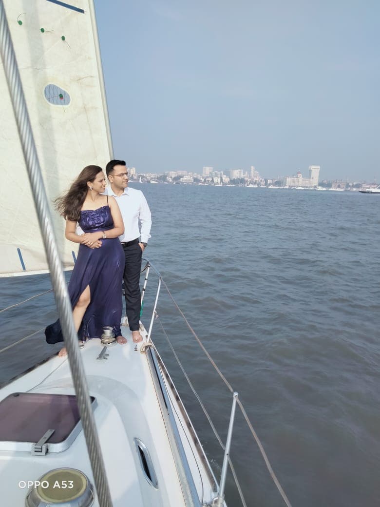 A couple standing at the bow under sail with the city skyline in view