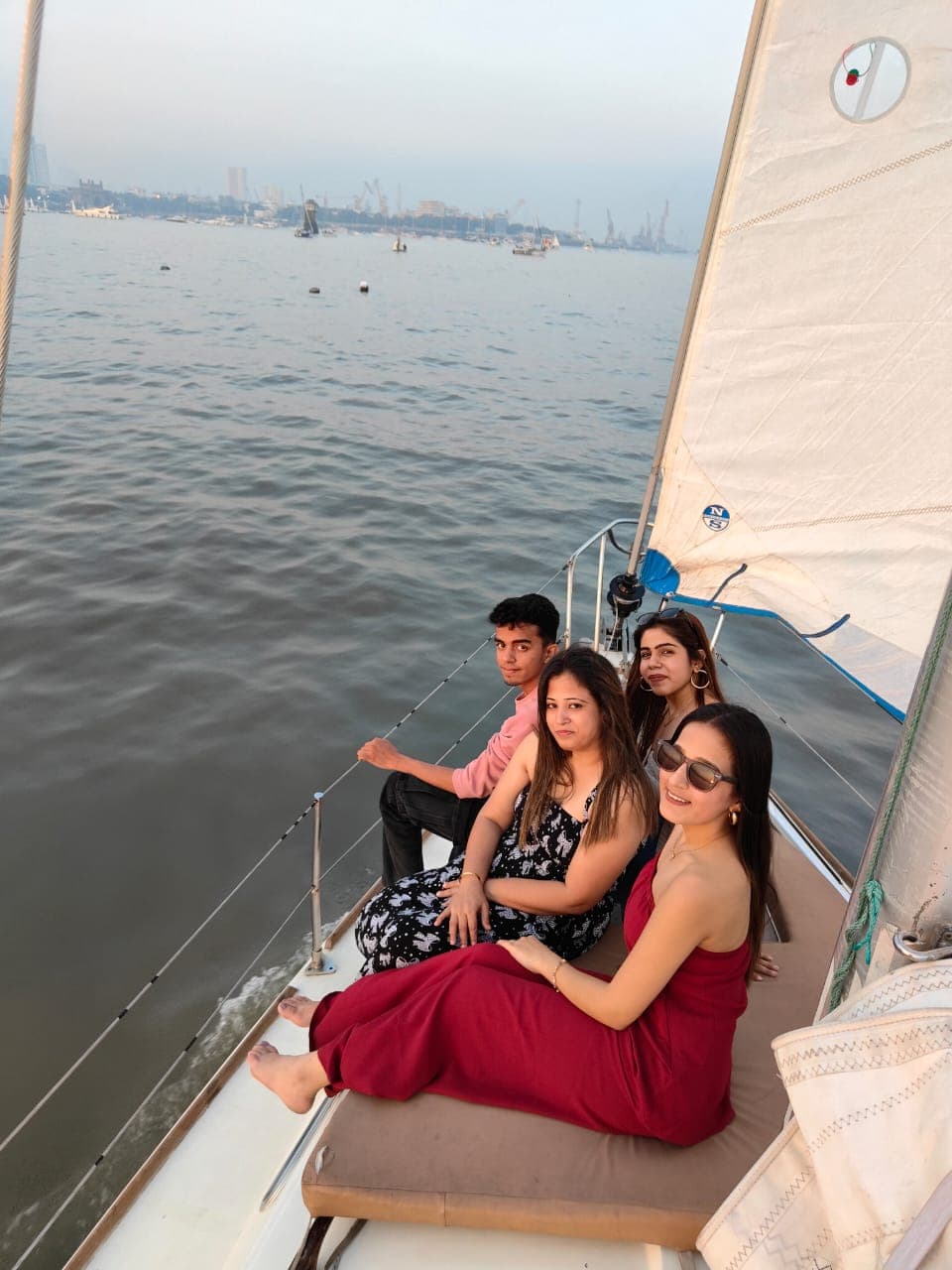 A group of friends seated at the bow at golden hour with the harbour behind