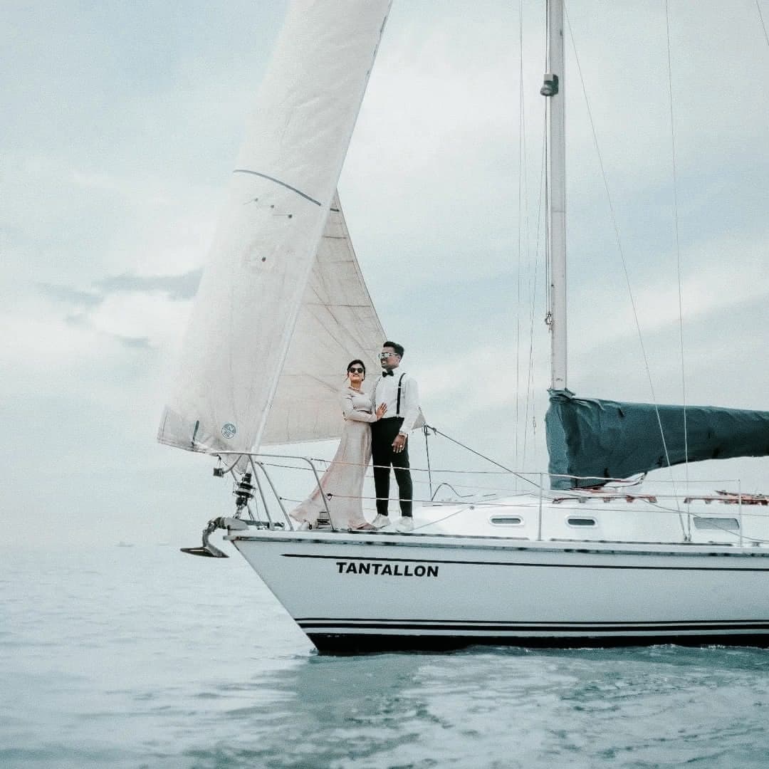 A couple in formal wear on the bow of Tantallon under sail, her name on the hull