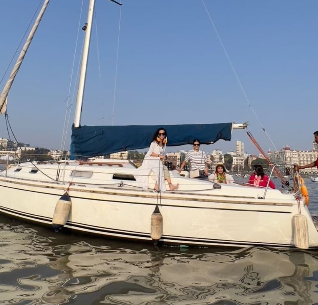 Tantallon under sail with guests seated at the bow, skyline behind