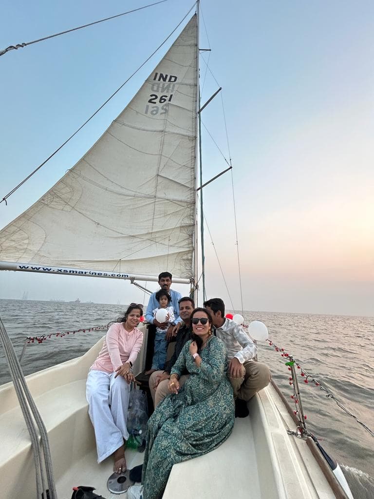 Guests seated on the bow under sail with the sail number IND 261 visible