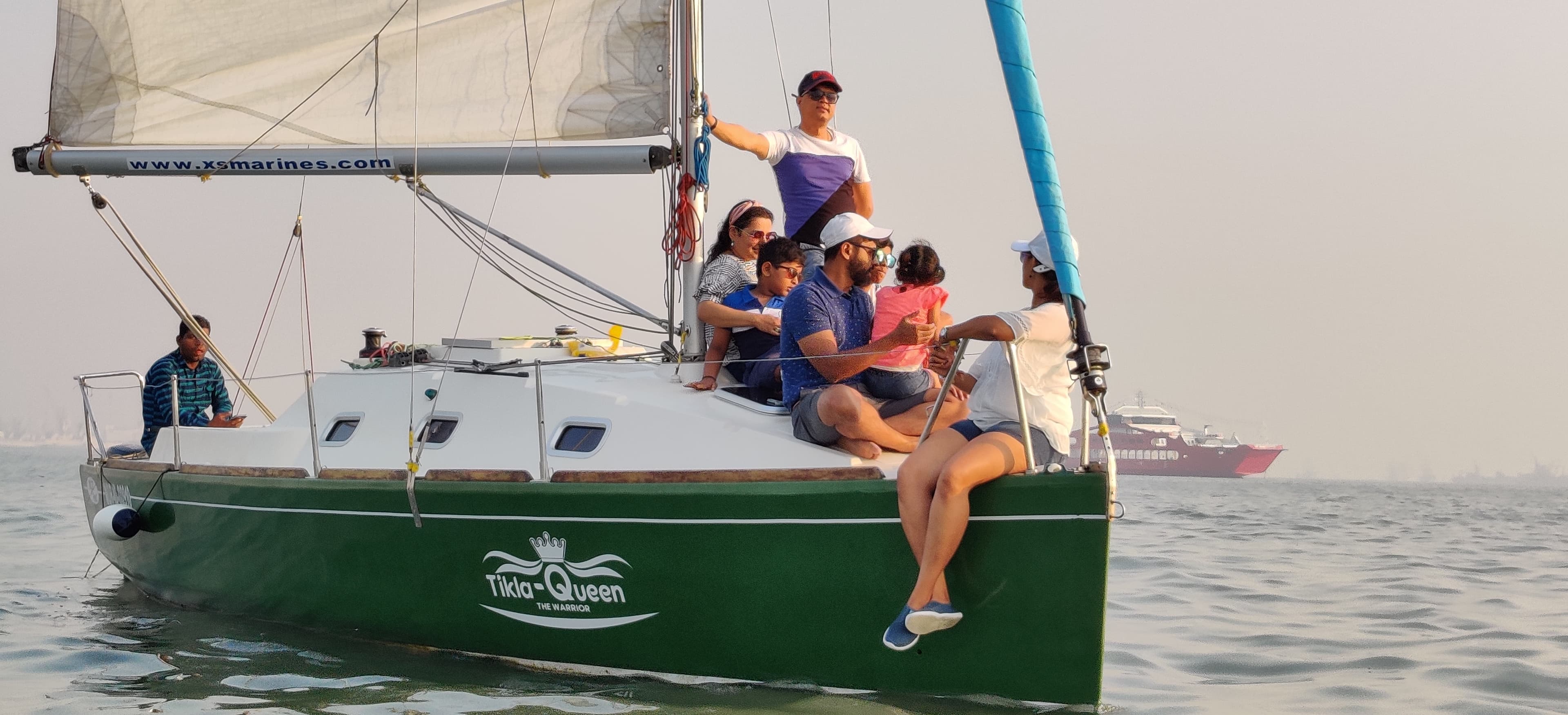 The skipper hoisting sail as a family of guests looks on