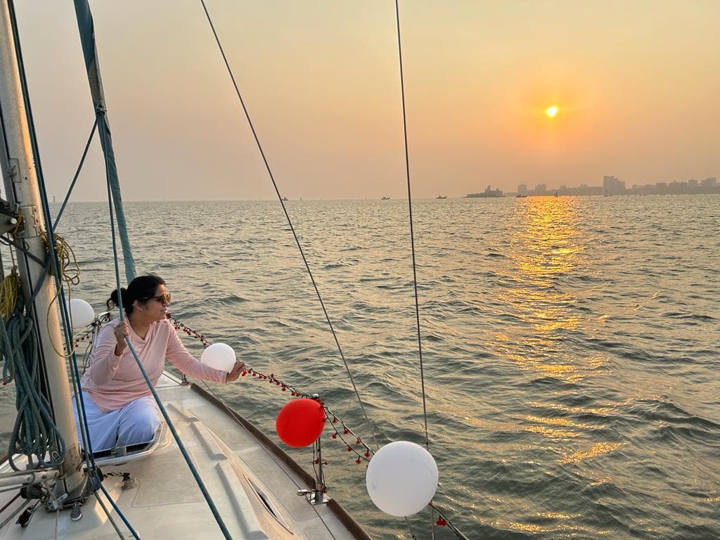 A guest at the bow at sunset with balloons strung along the rail