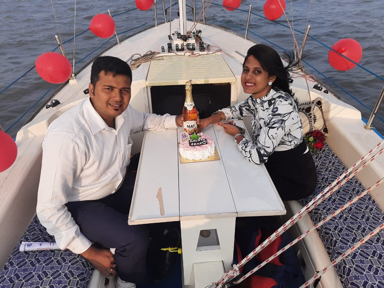A couple celebrating with a cake and bottle of sparkling fruit juice at the cockpit table