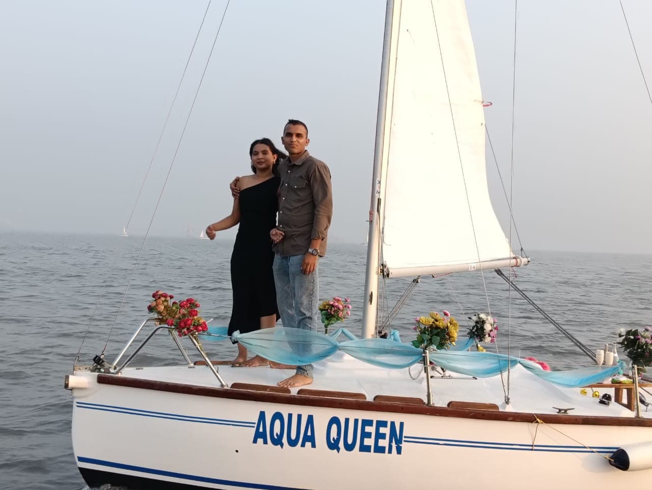 A couple standing at the bow of the sailboat Aqua Queen, decorated with fresh flowers