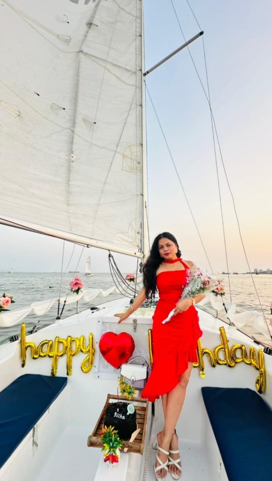 The sailboat Menaka near the jetty with guests boarding and rose bouquets on the bow, harbour boats behind
